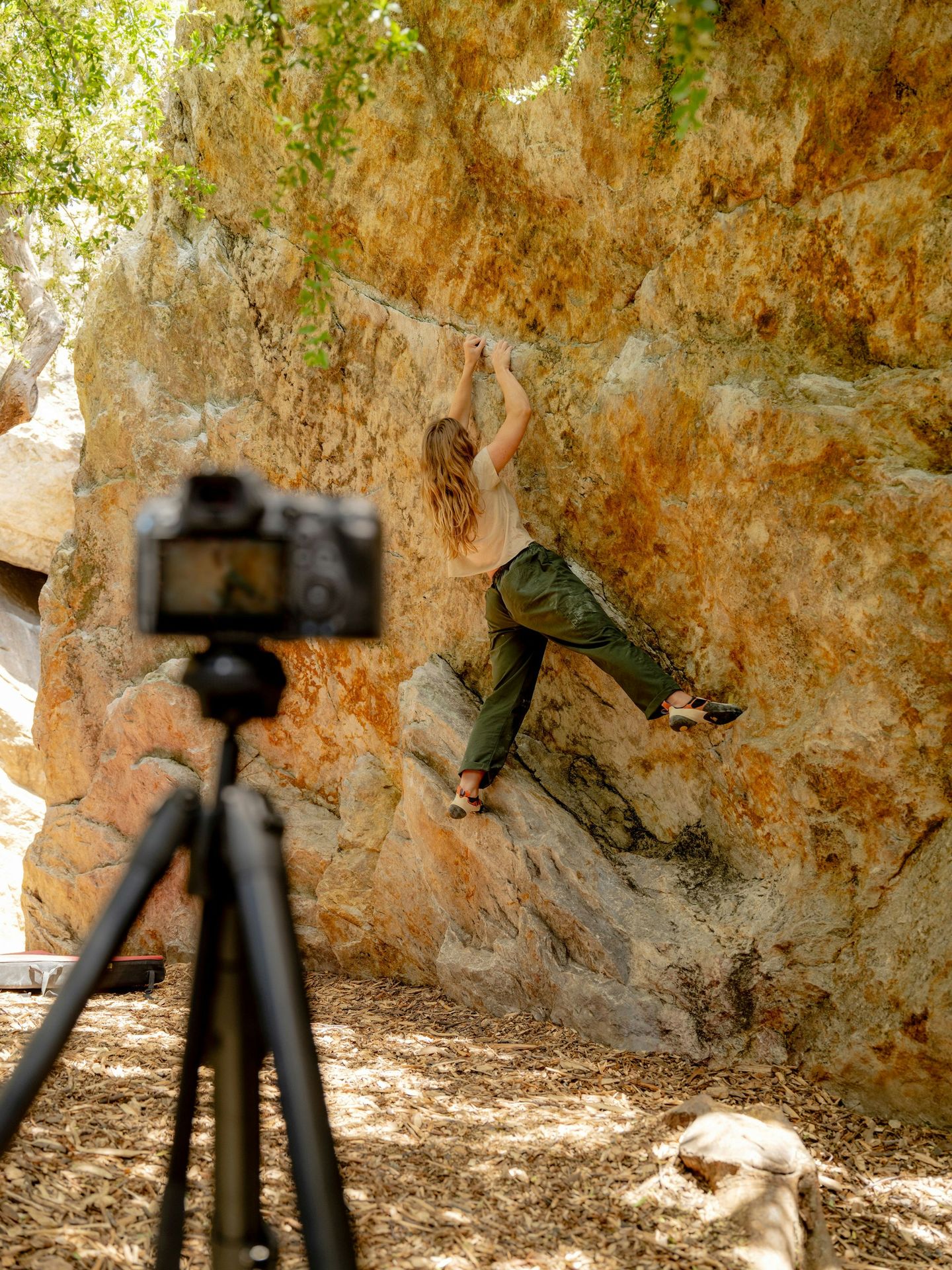 A man is climbing up a rock with a camera